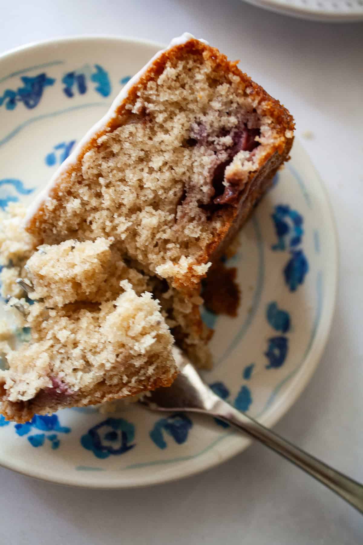 A fork cuts into a piece of gluten free berry cake.