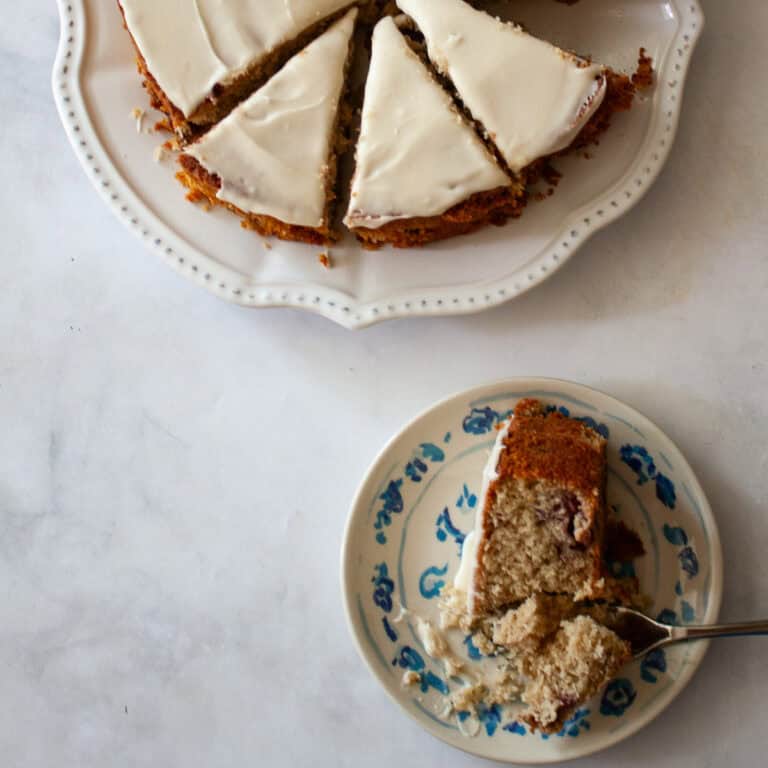 A sliced gluten free berry cake and a piece of cake on a plate.