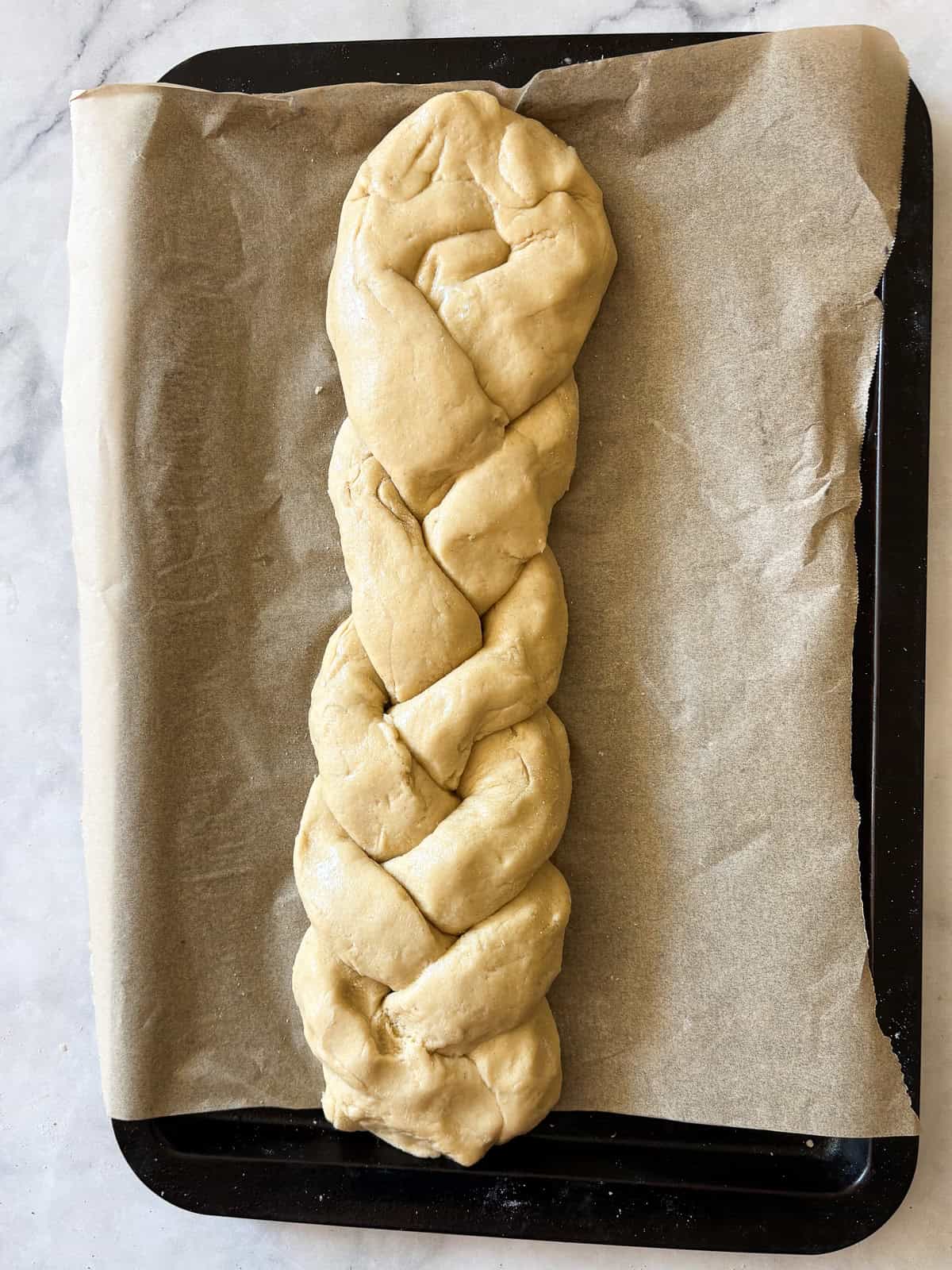 A gum-free recipe for a beautifully soft loaf of gluten free challah that's easy enough even for novice gluten-free bread bakers. A loaf of braided gluten free challah waits to bake.