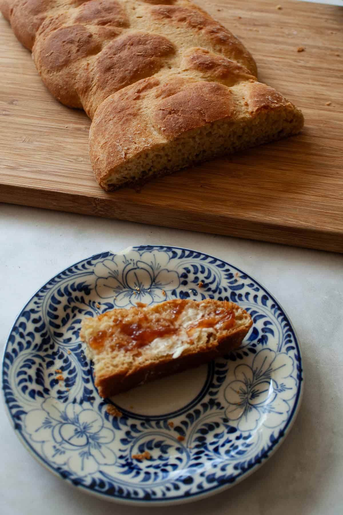 A gum-free recipe for a beautifully soft loaf of gluten free challah that's easy enough even for novice gluten-free bread bakers. A gluten free challah loaf on a cutting board and a slice in front of it.