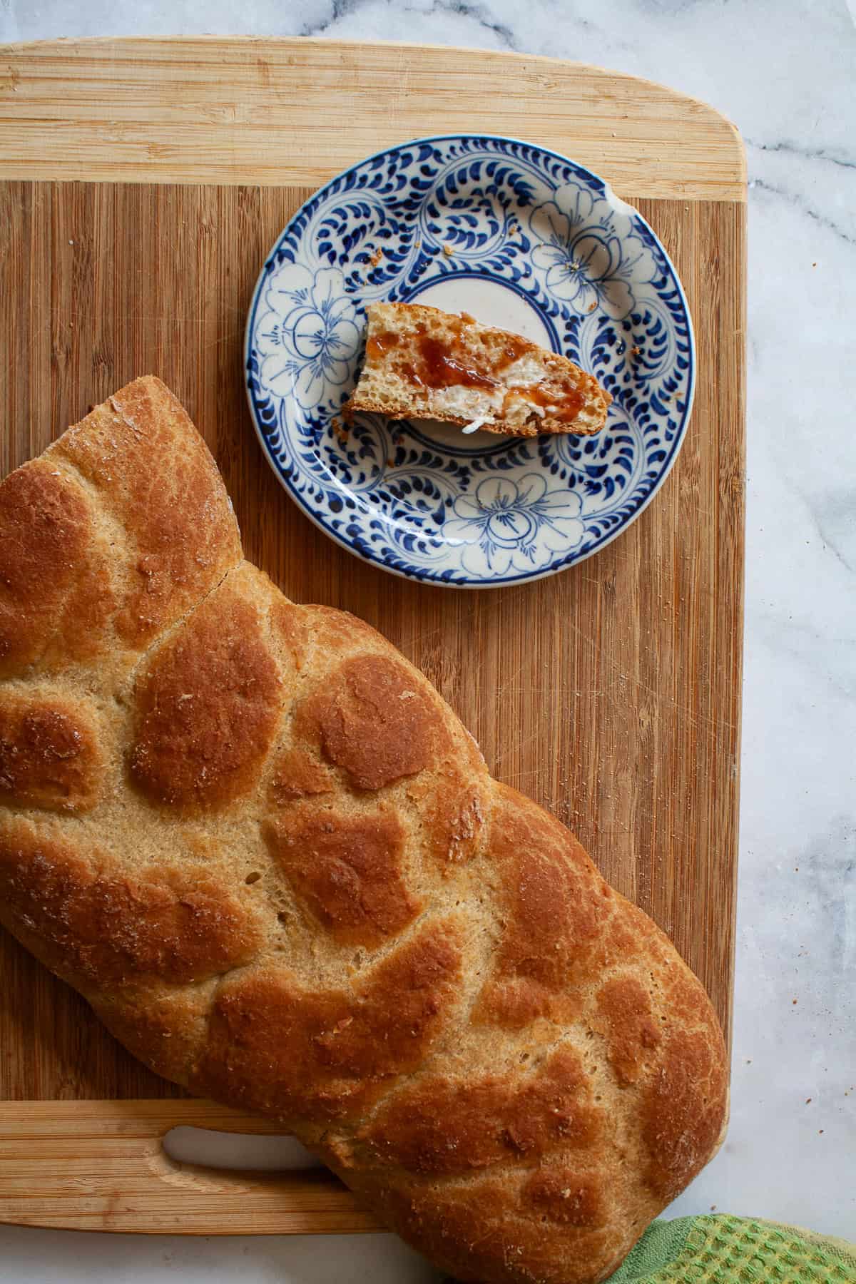 A golden braided loaf of gluten free challah and a slice of challah on a plate.