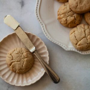 A gluten free cream biscuit on a plate with a knife next to the plate of biscuits.