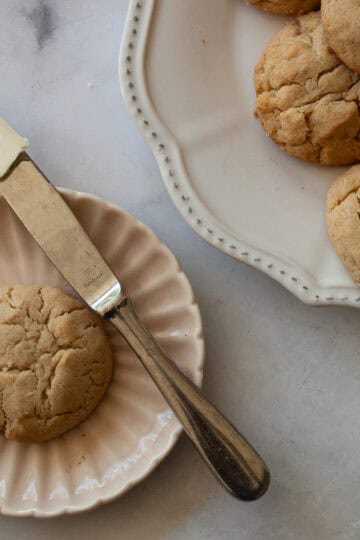 A gluten free cream biscuit on a plate with a knife next to the plate of biscuits.