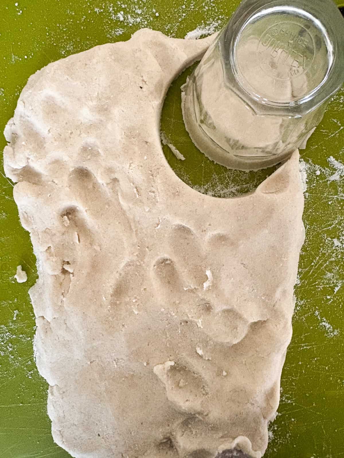 Tender and just lightly sweet gluten free cream biscuits are made in just one bowl with a handful of simple ingredients! Cutting out biscuit dough with a glass.