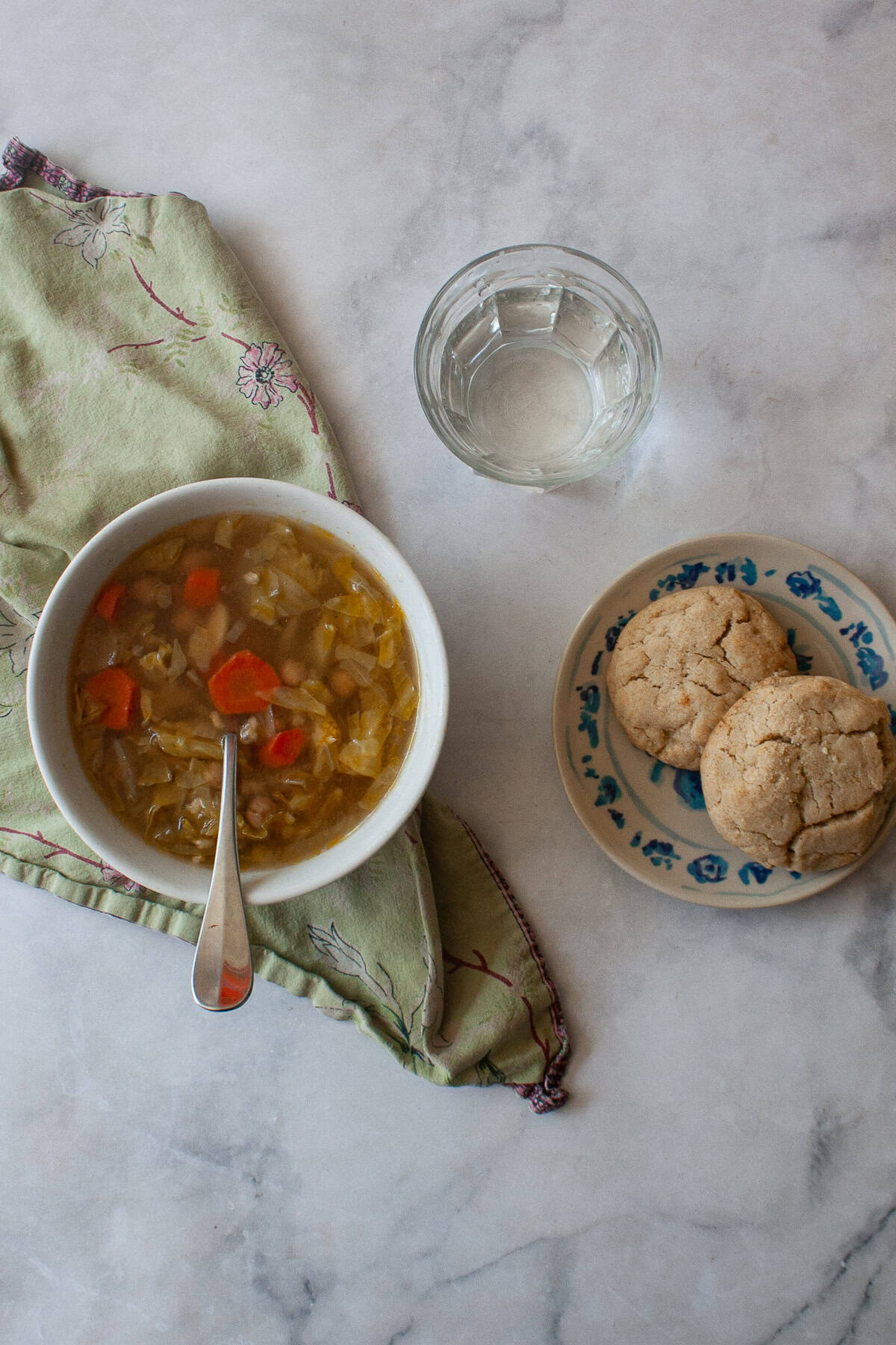 A brothy, satisfying vegetarian soup packed with tender cabbage, carrots, onions, garlic and plenty of chewy brown rice. A bowl of vegetarian cabbage soup is served with biscuits and a glass of water.