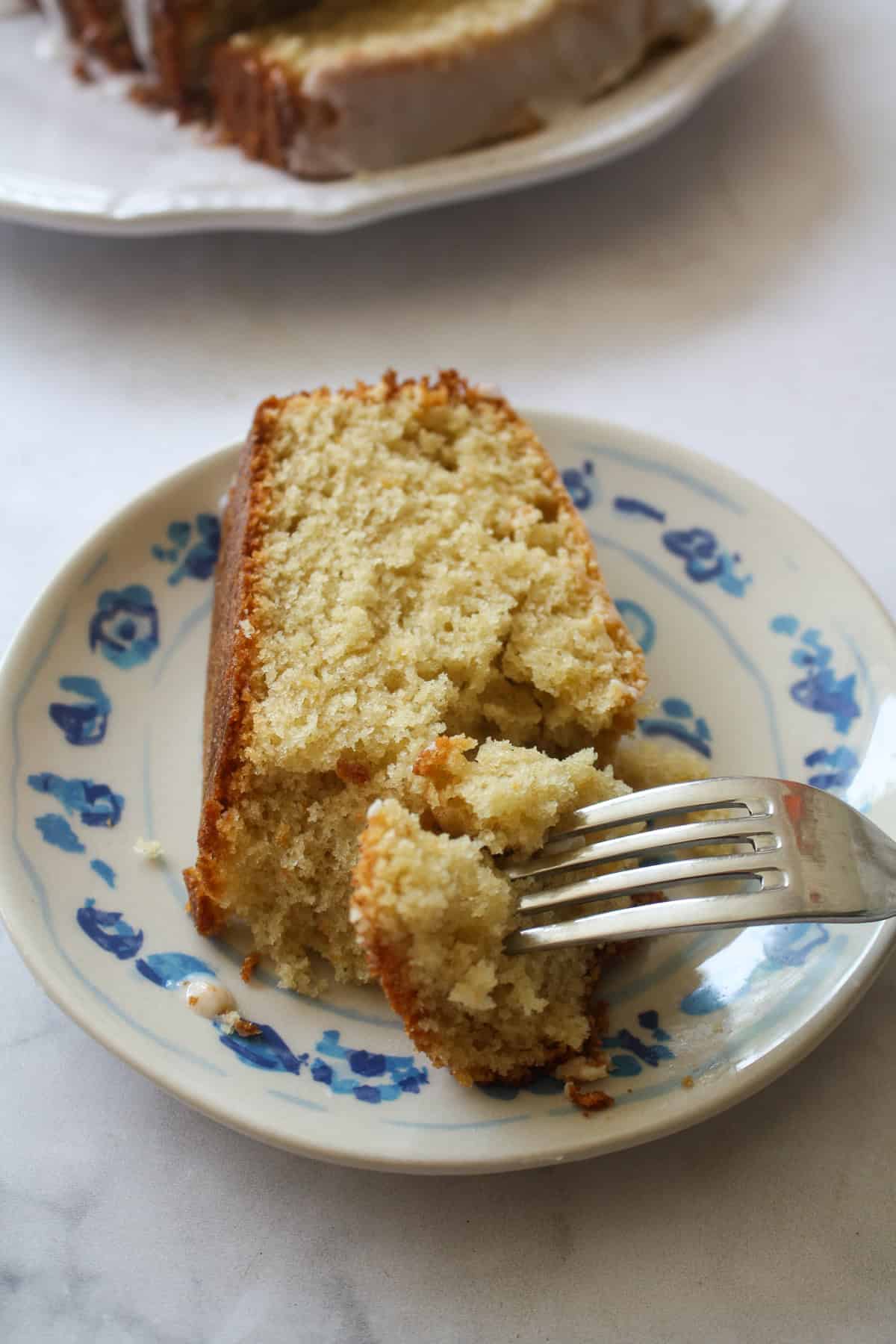 A tender and moist yogurt-based crumb makes this pretty gluten free olive oil grapefruit cake stand out. Finished with grapefruit glaze! A fork cuts into a slice of gluten free grapefruit bread.