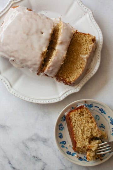 A slice of gluten free grapefruit bread on a plate with a sliced loaf nearby/