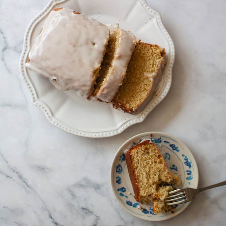 A slice of gluten free grapefruit bread on a plate with a sliced loaf nearby/