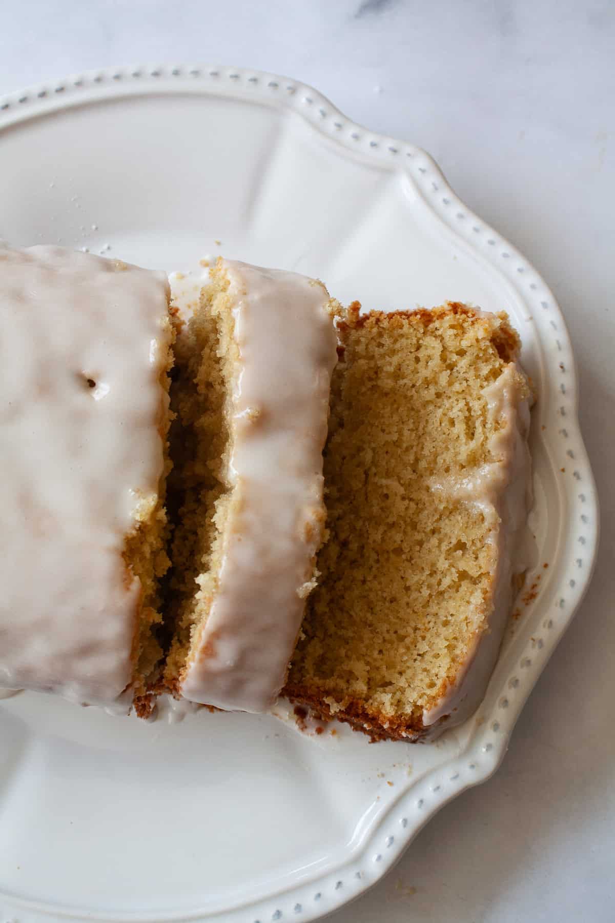 A tender and moist yogurt-based crumb makes this pretty gluten free olive oil grapefruit cake stand out. Finished with grapefruit glaze! A sliced loaf of gluten free grapefruit bread on a plate.