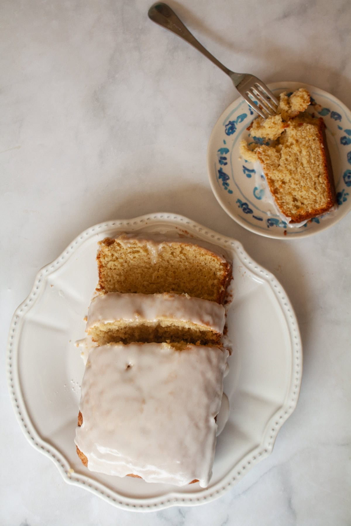A slice of gluten free grapefruit bread on a plate with a sliced loaf nearby.