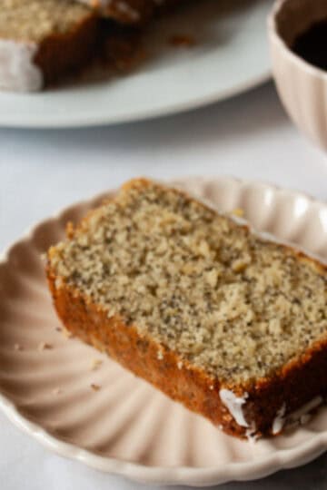 Gluten free lemon poppyseed bread on a plate with a cup of coffee.