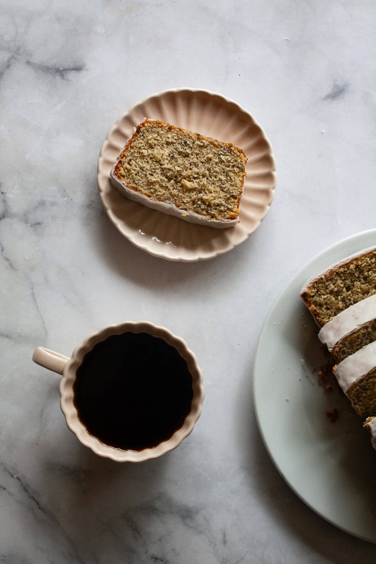 A tender, gorgeously sliceable gluten free lemon poppyseed bread topped with a bright, thick lemon glaze for maximum flavor. A cup of coffee and a slice of gluten free lemon poppyseed bread.