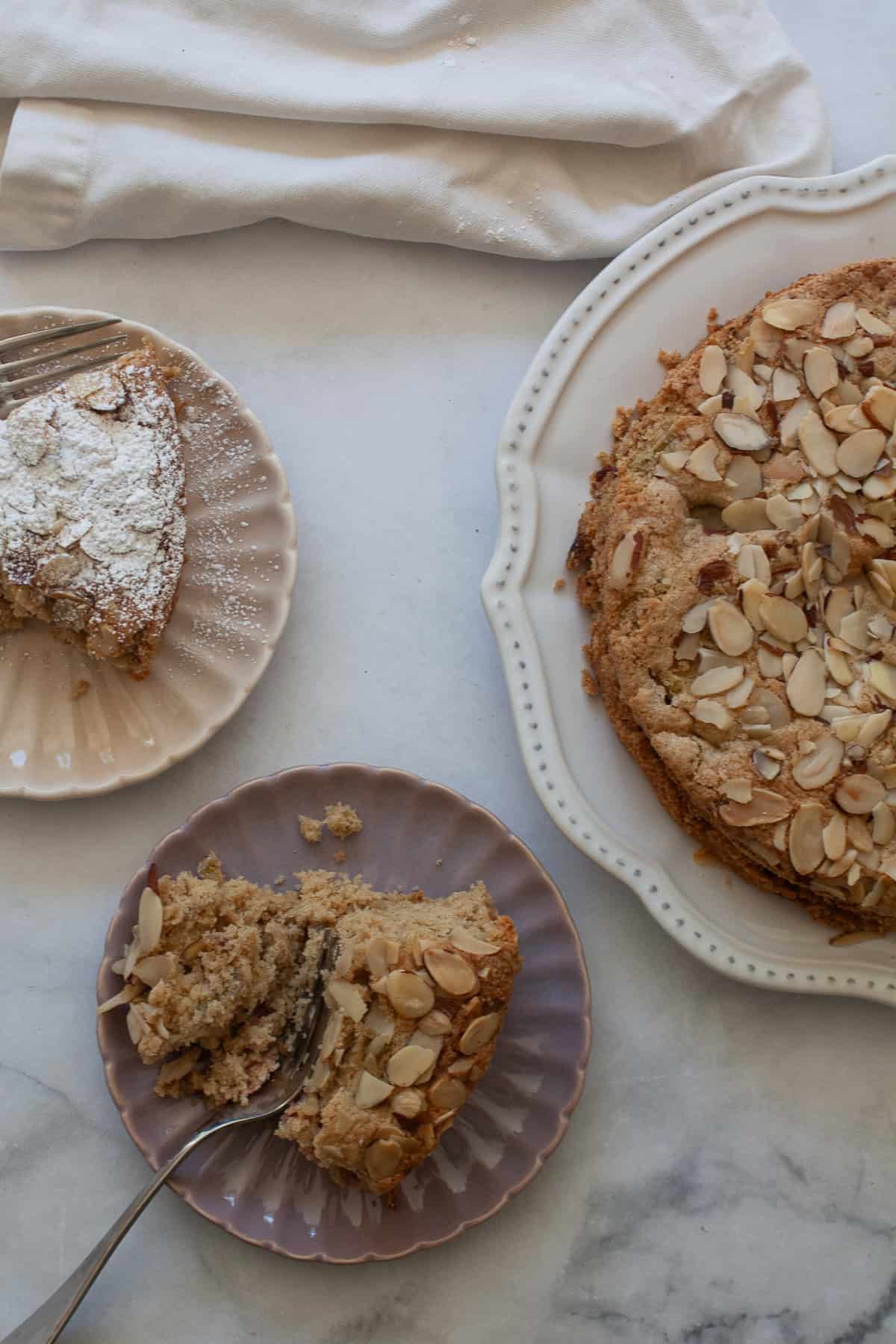 Tart rhubarb is the star of this gluten free rhubarb cake, with jammy pockets of rhubarb and a soft-crumbed cake that's just sweet enough. A fork cuts into a piece of gluten free rhubarb cake with cake and another slice nearby.