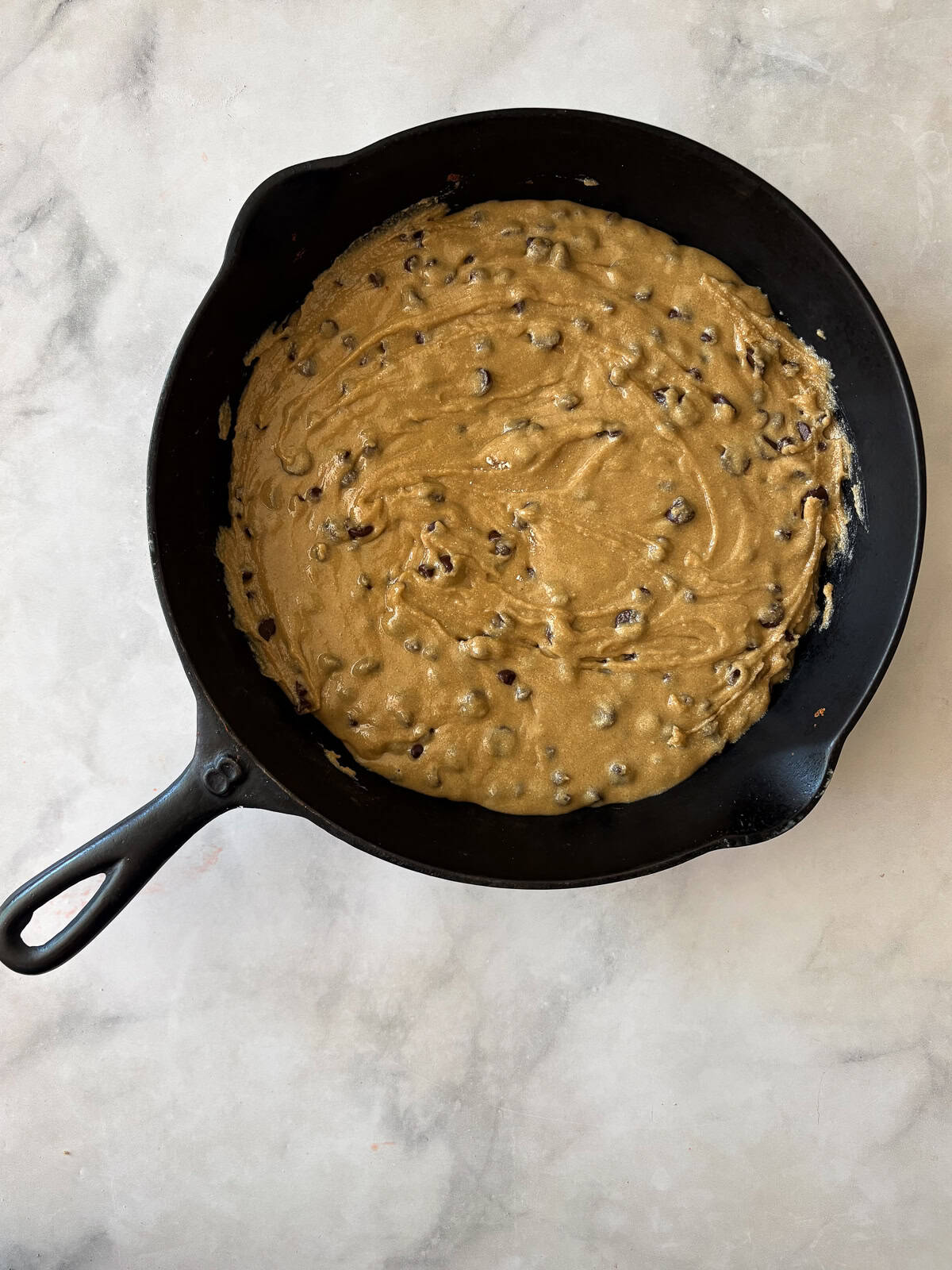 This sweet and chewy gluten free skillet cookie that's soooo good served warm and topped with ice cream. Made in one bowl! Batter for gluten free skillet cookie added to a skillet.