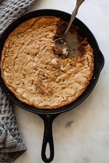 A serving spoon rests in a gluten free skillet cookie.
