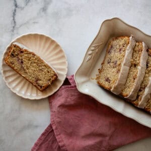 A slice of gluten free strawberry loaf cake on a plate and slices in a serving dish.