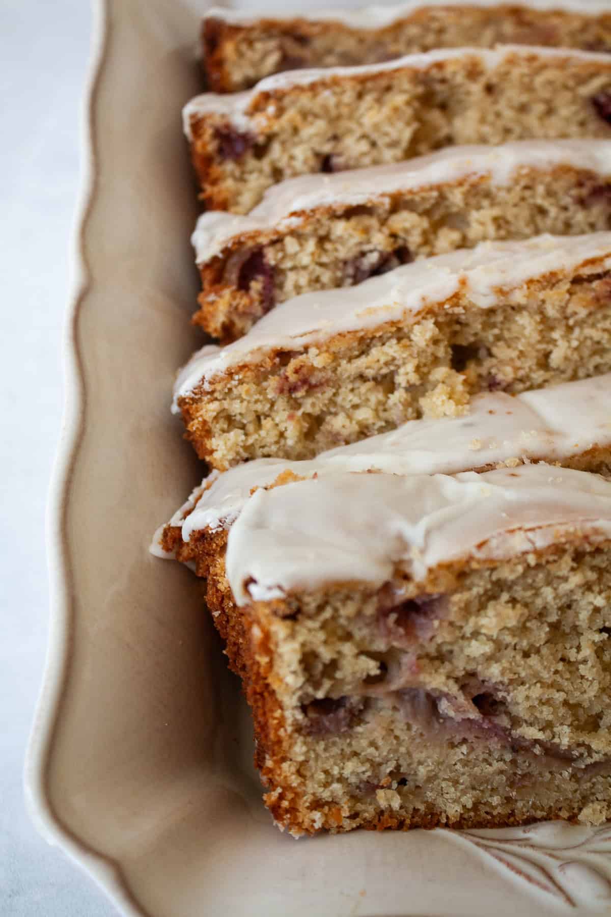 A tender, fruit-flecked gluten-free strawberry loaf cake topped with a simple and sweet vanilla glaze. The best summery bake! Vanilla glaze tops slices of gluten free strawberry loaf cake.