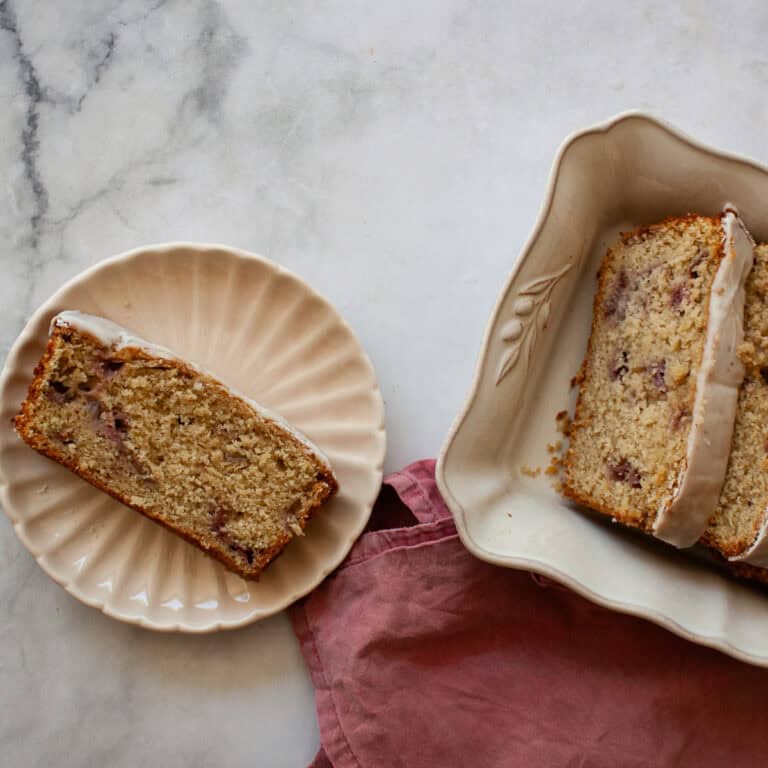 A slice of gluten free strawberry loaf cake on a plate and slices in a serving dish.