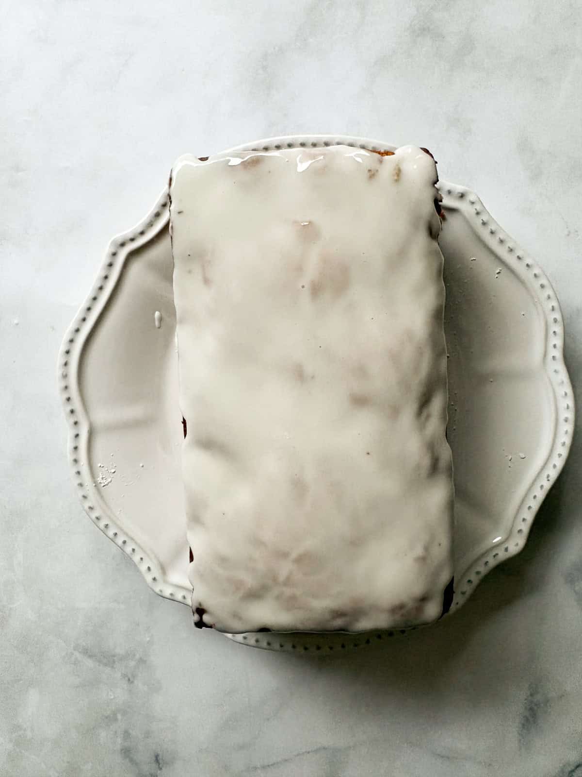 A tender, fruit-flecked gluten-free strawberry loaf cake topped with a simple and sweet vanilla glaze. The best summery bake! A gluten free strawberry loaf cake is topped with vanilla glaze.