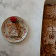 A slice of gluten free strawberry rhubarb cake on a plate next to the cake.