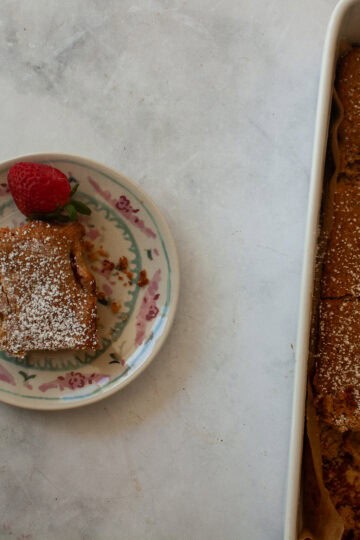 A slice of gluten free strawberry rhubarb cake on a plate next to the cake.