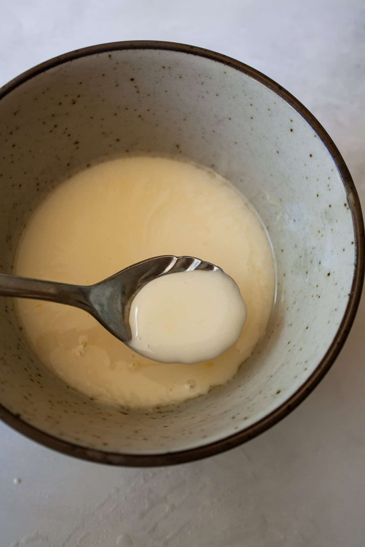 This two-ingredient orange glaze adds sweet citrus flavor to cakes, quick breads, scones, muffins, and more! A spoon lifts up a little bit of orange glaze.