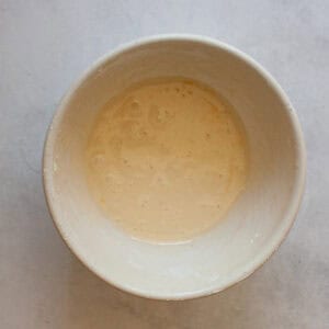 A small white bowl of orange glaze.