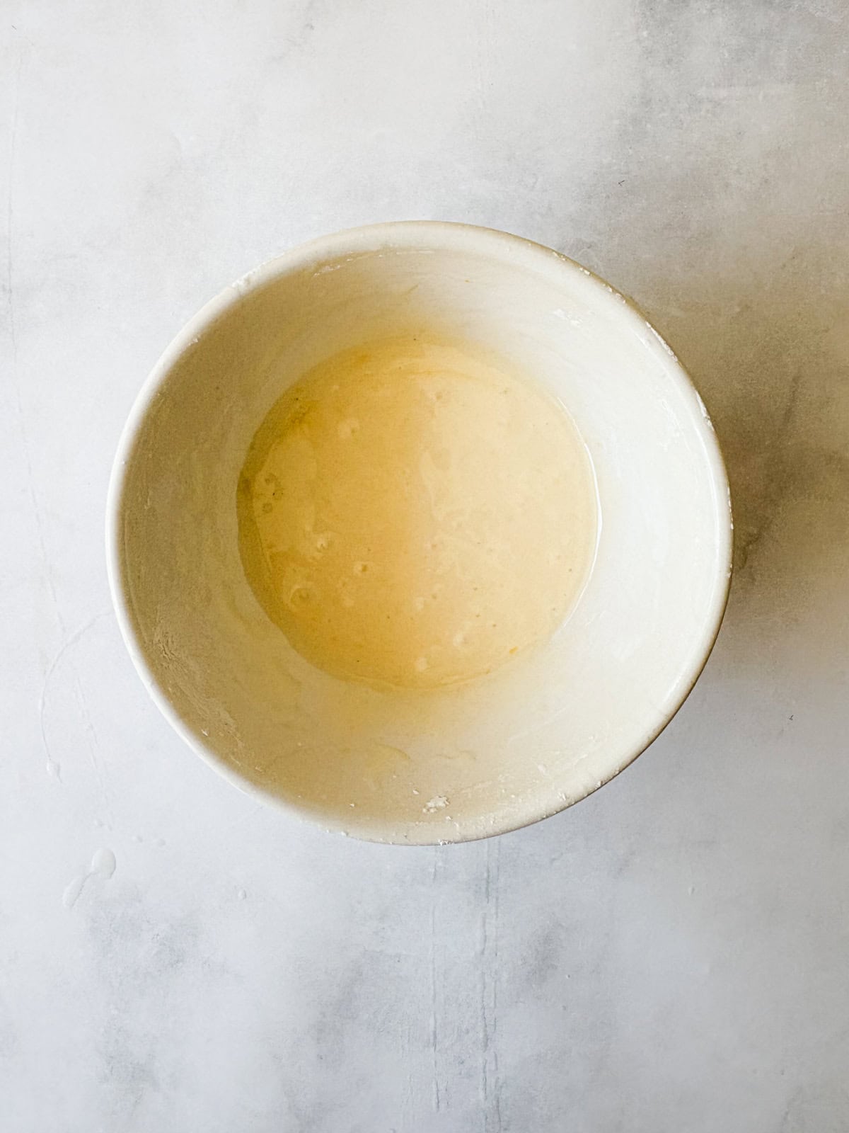 This two-ingredient orange glaze adds sweet citrus flavor to cakes, quick breads, scones, muffins, and more! The orange glaze after being whisked in a bowl.