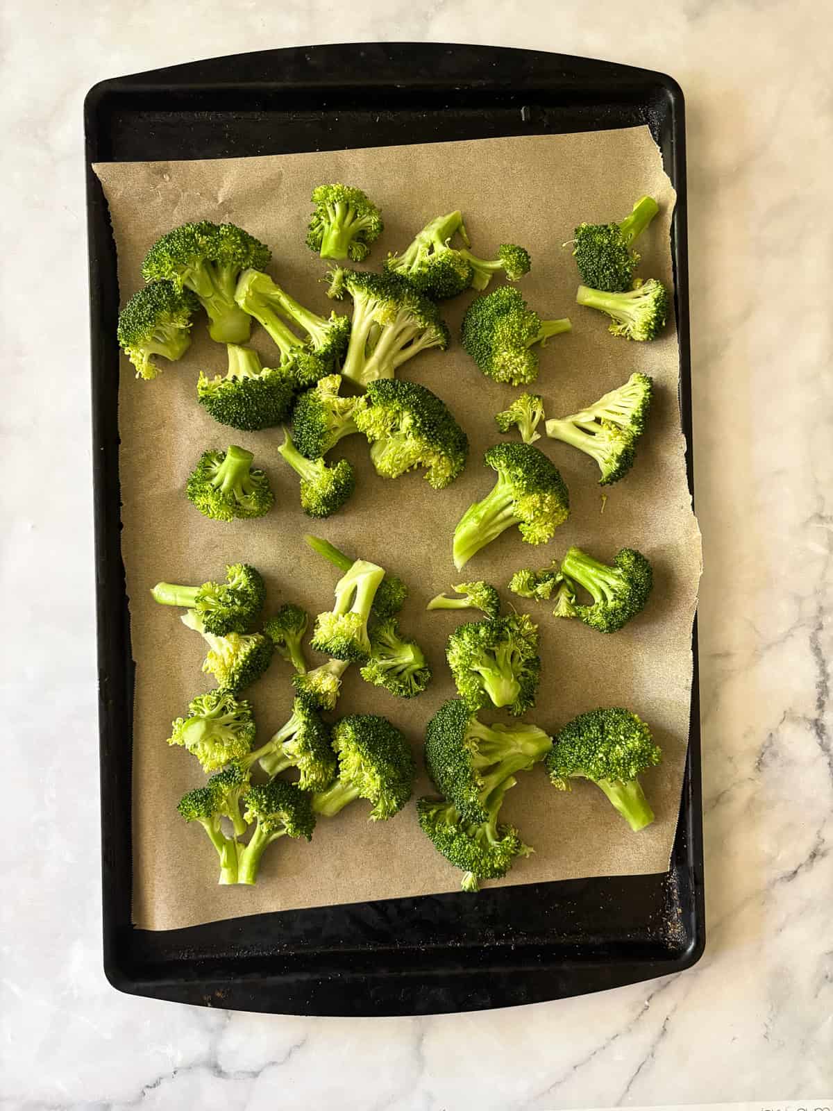 An easy recipe for roasted broccoli that can be boosted with lemon juice or zest, garlic, red pepper flakes - or simply dusted with Parmesan. Broccoli is spread out on a lined baking sheet.