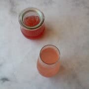 A rhubarb cocktail in front of a jar of rhubarb simple syrup.