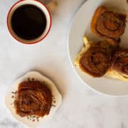 A cup of coffee next to plates of sticky buns.