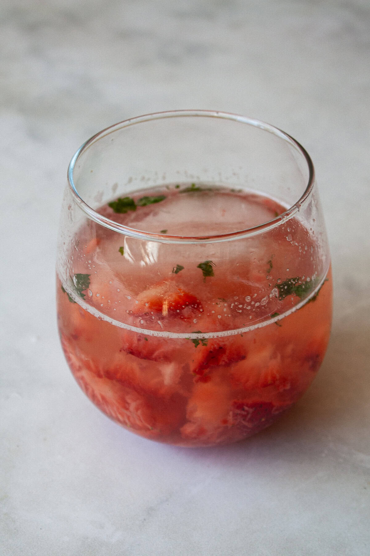 This strawberry mocktail is a not-too-sweet, non-alcoholic drink featuring juicy strawberries muddled with honey, lime, and mint. A glass of strawberry mocktail with mint.