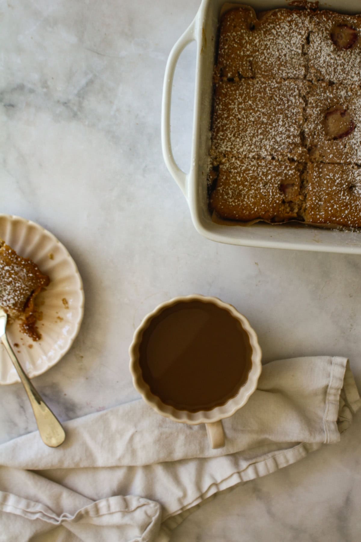 A tender strawberry rhubarb cake made with whole wheat flour, fresh fruit, and a buttery crumb. Rustic, easy, and perfect for summer baking. A pan of strawberry rhubarb cake, a coffee, and a slice on a plate.