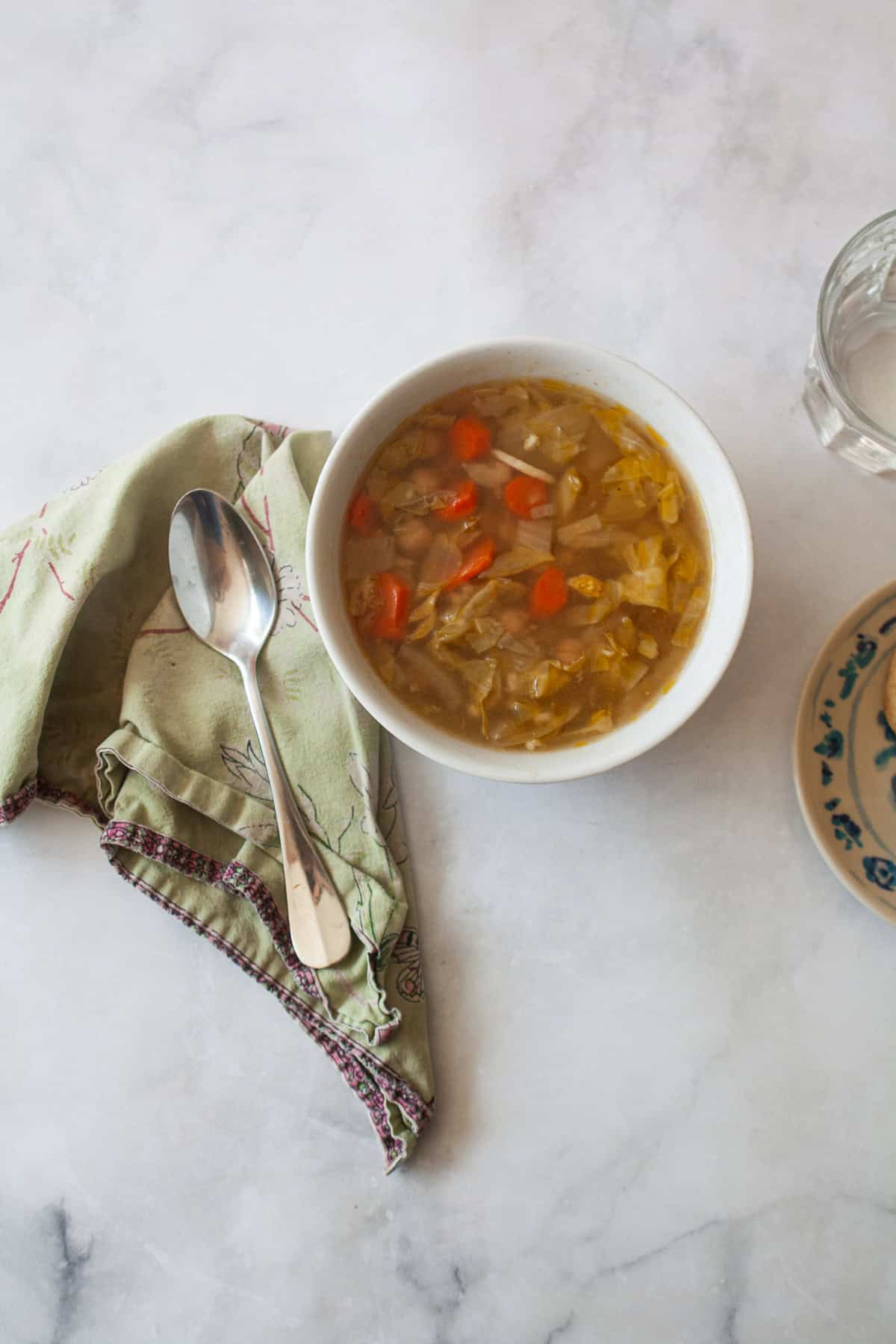 A bowl of vegetarian cabbage soup with a napkin and spoon.