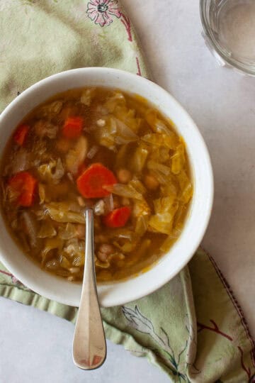 A bowl of vegetarian cabbage with a spoon in it on a green napkin.