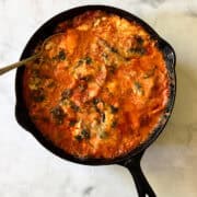 A serving spoon inserted into a pan of gluten free skillet lasagna.