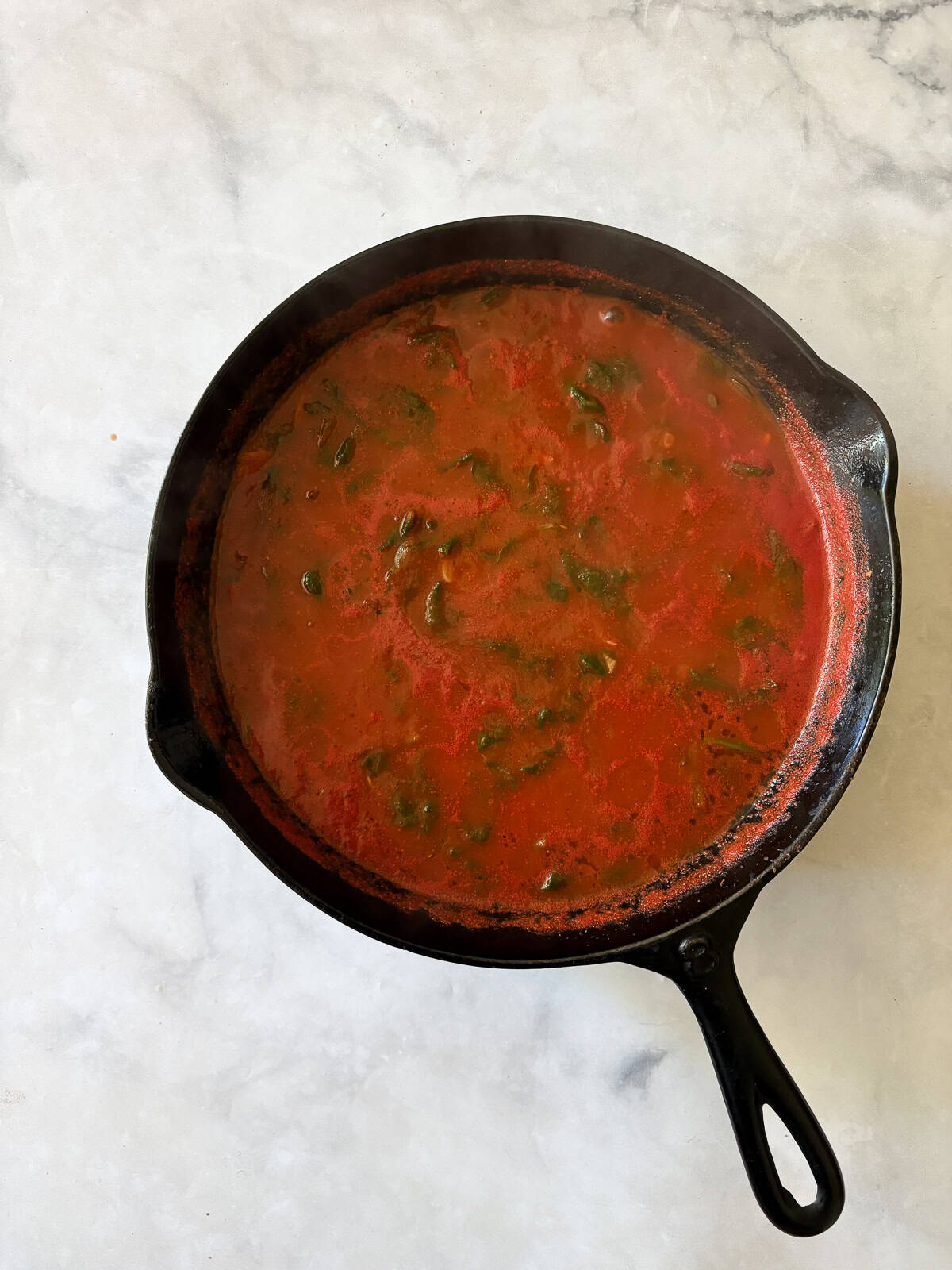Tomato sauce simmers for gluten free skillet lasagna.