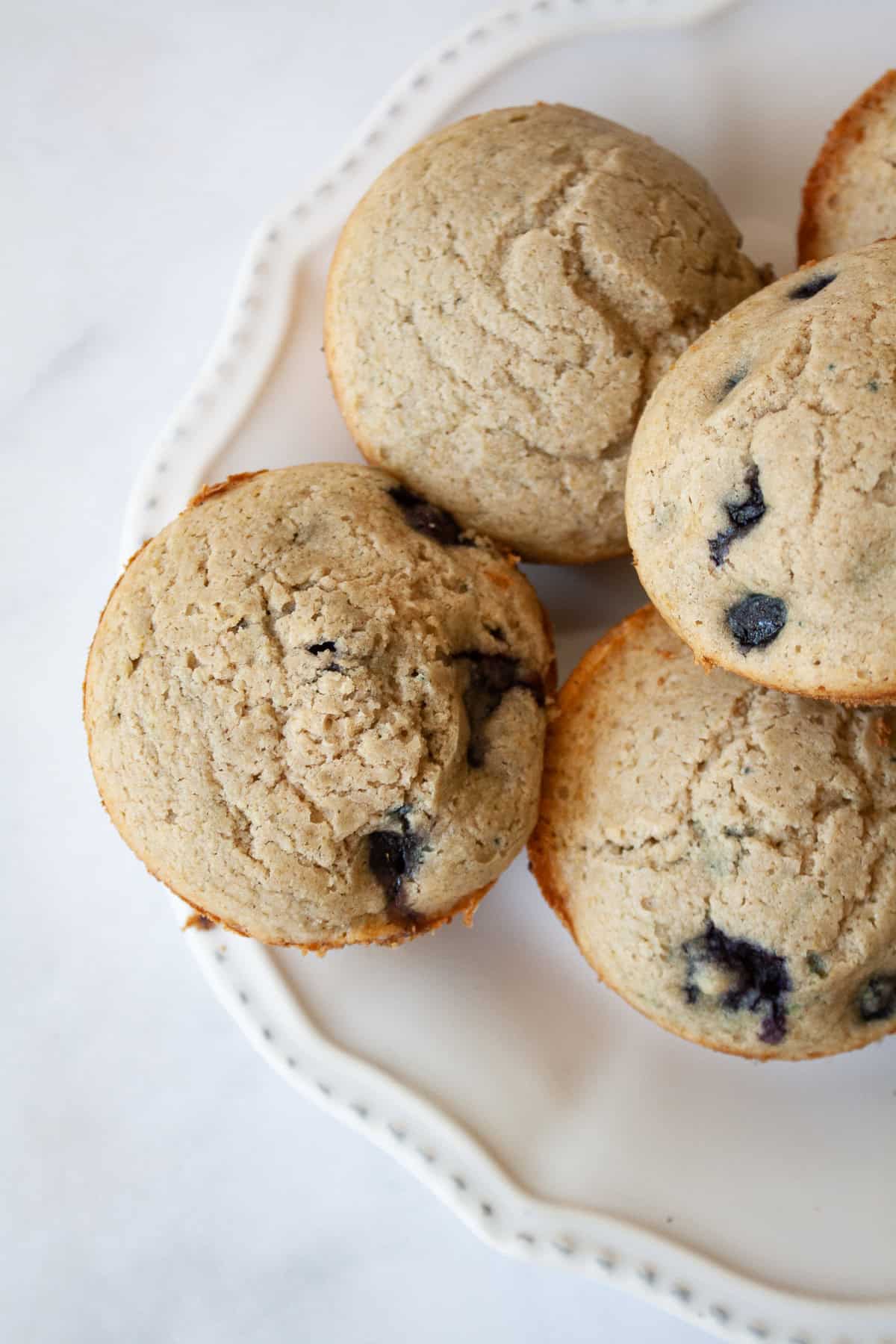 These heart-healthy whole wheat blueberry muffins are a family favorite, made with loads of juicy berries and sweetened with maple syrup. A plate of whole wheat blueberry muffins.