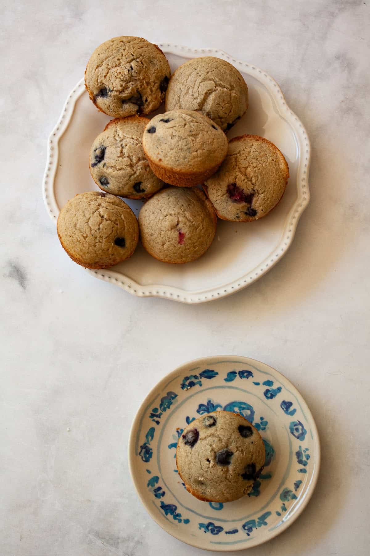 These heart-healthy whole wheat blueberry muffins are a family favorite, made with loads of juicy berries and sweetened with maple syrup. A plate of whole wheat blueberry muffins and a muffin on a plate.