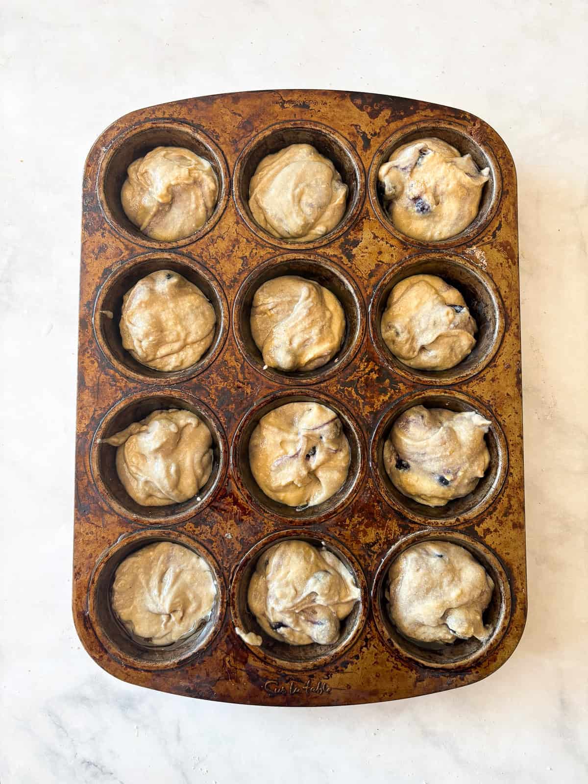 Sweet and tender gluten free lemon blueberry muffins feature loads of juicy berries, lemon zest, and an easy batter that bakes up perfectly. Whole wheat blueberry muffins batter in a muffin tin.