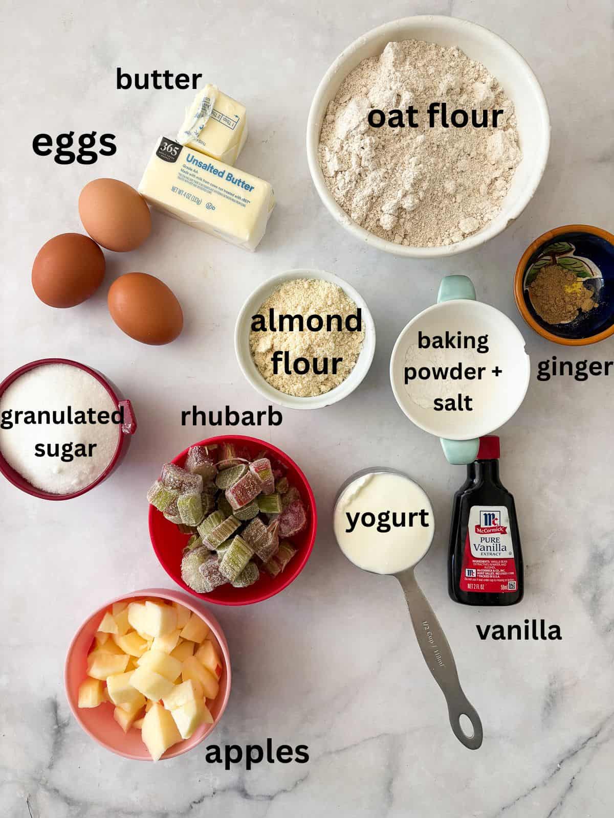 This pretty cake marries crisp, sweet apples with tart rhubarb to make a seasonal gluten free apple and rhubarb cake! Ingredients for gluten free apple and rhubarb cake are text-labeled.