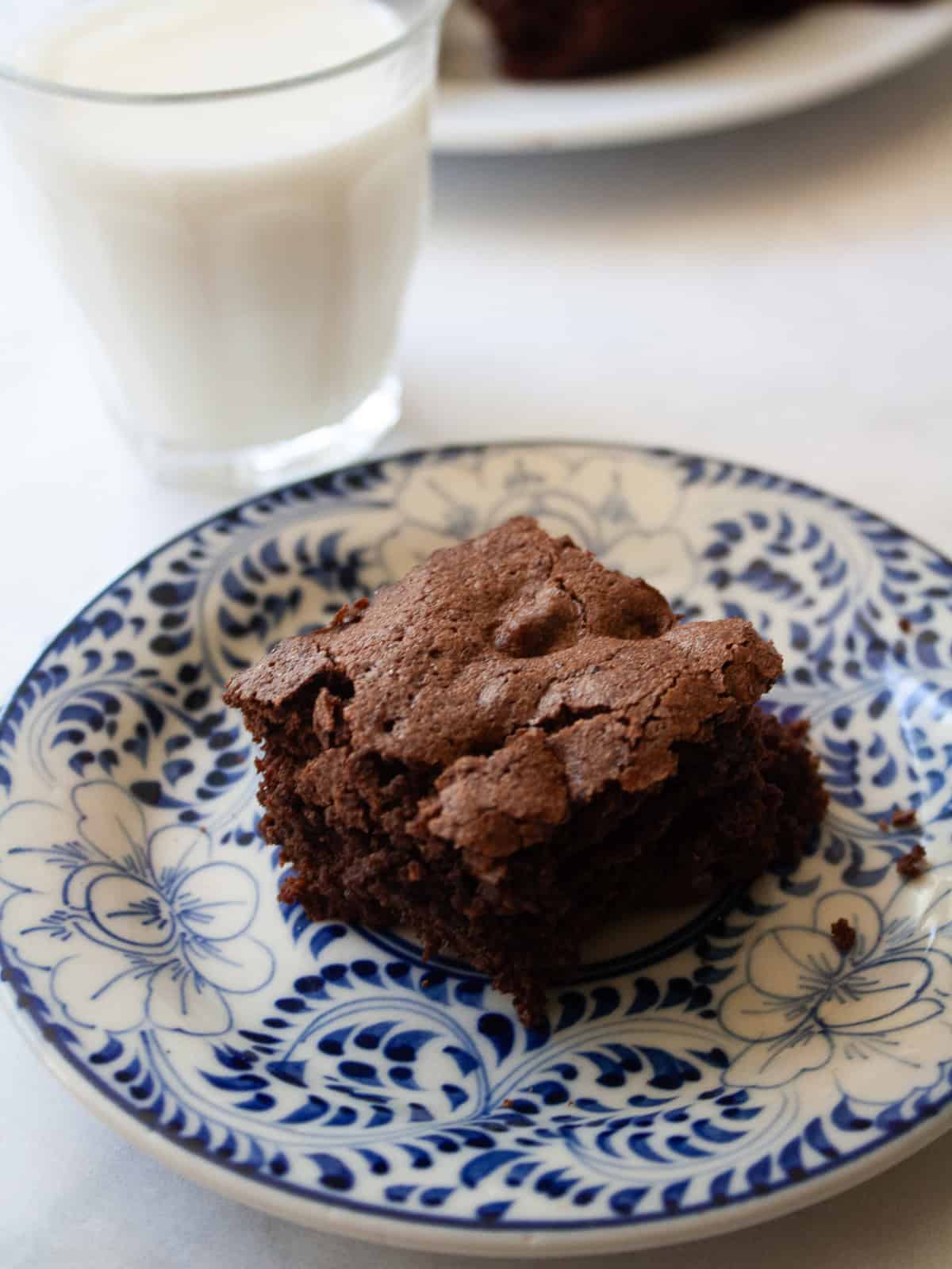 Deeply rich and chocolatey almond flour brownies are both grain-free and gluten-free. So much better than a boxed mix! A glass of milk next to an almond flour brownie on a plate.