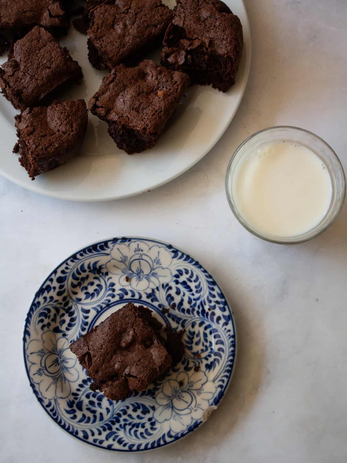 Deeply rich and chocolatey almond flour brownies are both grain-free and gluten-free. So much better than a boxed mix! An almond flour brownie on a decorative plate with a glass of milk.