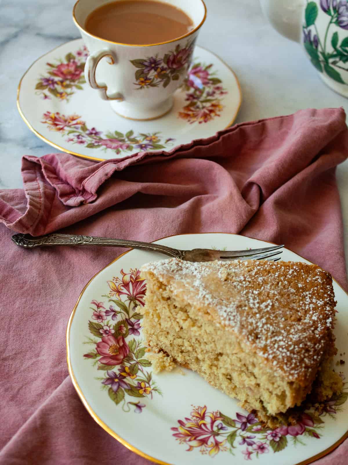 A nubbly and wholesome apple rhubarb cake that's made with whole-grain flour, yogurt, and plenty of juicy apples and tart rhubarb. A fork rests on a plate next to a slice of apple rhubarb cake.