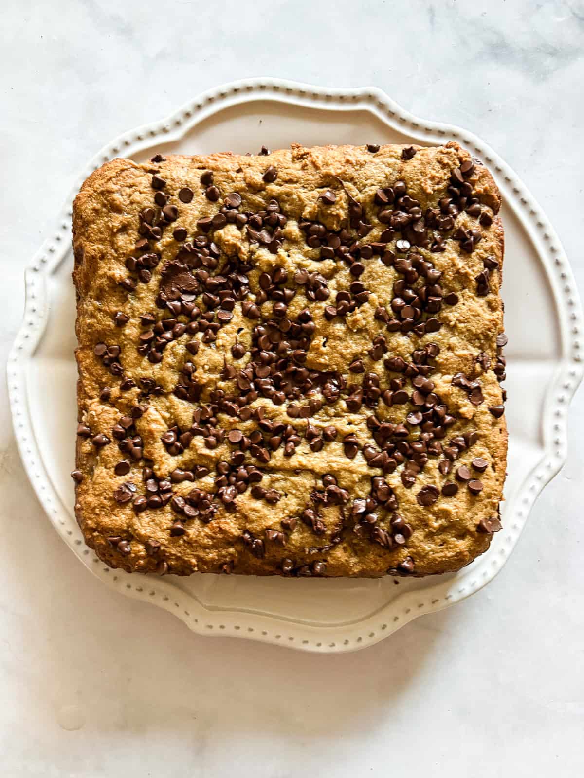 This banana snack cake is fluffy, moist, and balanced by warming spices. Naturally gluten-free, or make it with whole wheat flour. A baked banana snack cake topped with chocoalte chips.