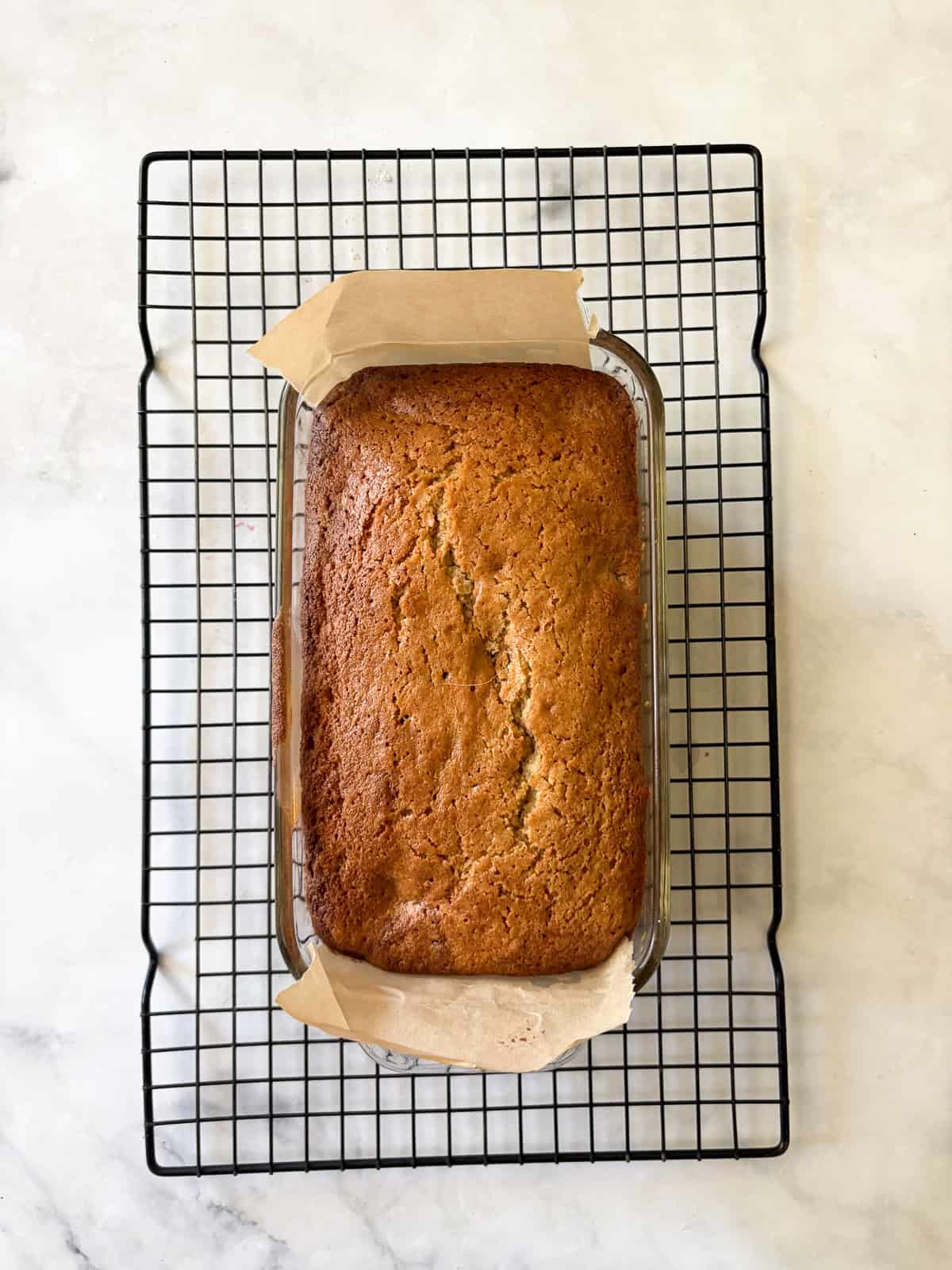 A recipe for a one-bowl gluten free cherry loaf cake that's swirled with chopped cherries and finished with a slick of tart lemon glaze. A baked gluten free cherry loaf cake cools in a loaf pan.