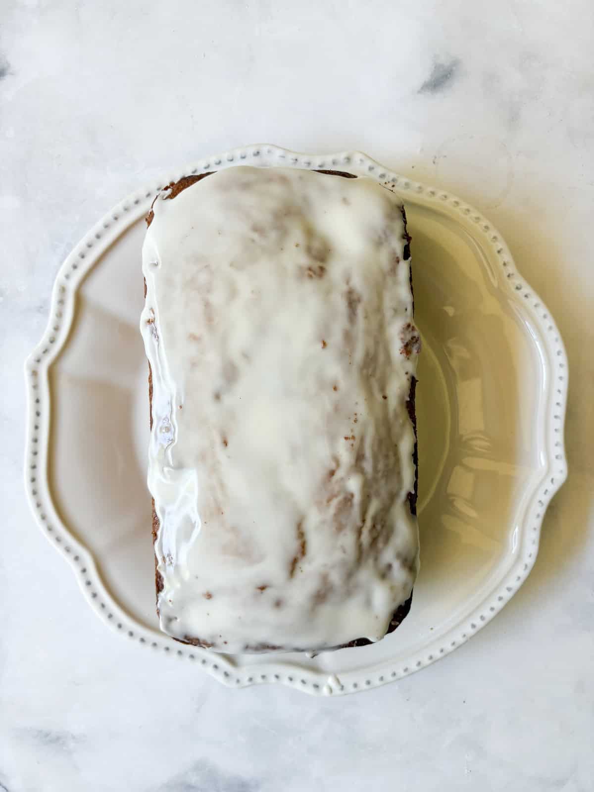 A recipe for a one-bowl gluten free cherry loaf cake that's swirled with chopped cherries and finished with a slick of tart lemon glaze. The finished loaf of gluten free cherry loaf cake topped with lemon glaze.