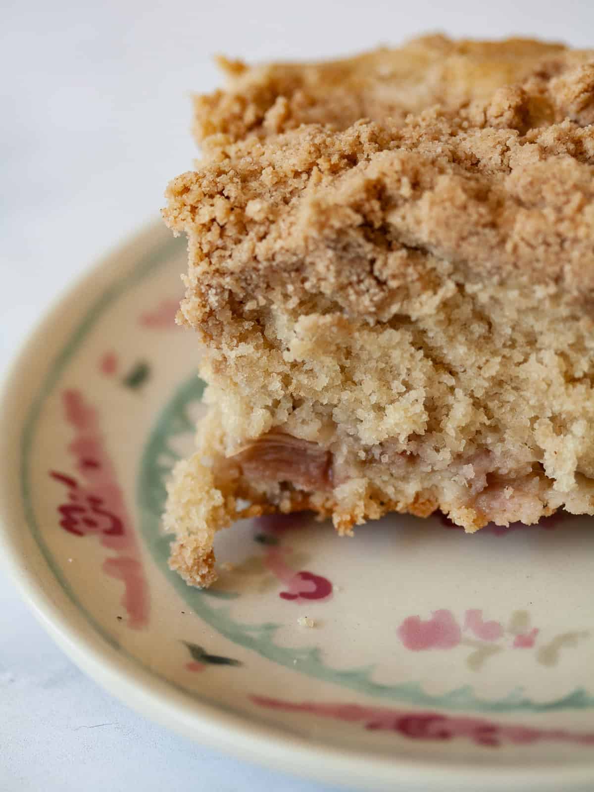 A soft and sweet gluten free rhubarb crumb cake with tart bits of rhubarb and a buttery, brown sugar streusel. Great for brunch! A slice of gluten free rhubarb crumb cake on a plate.