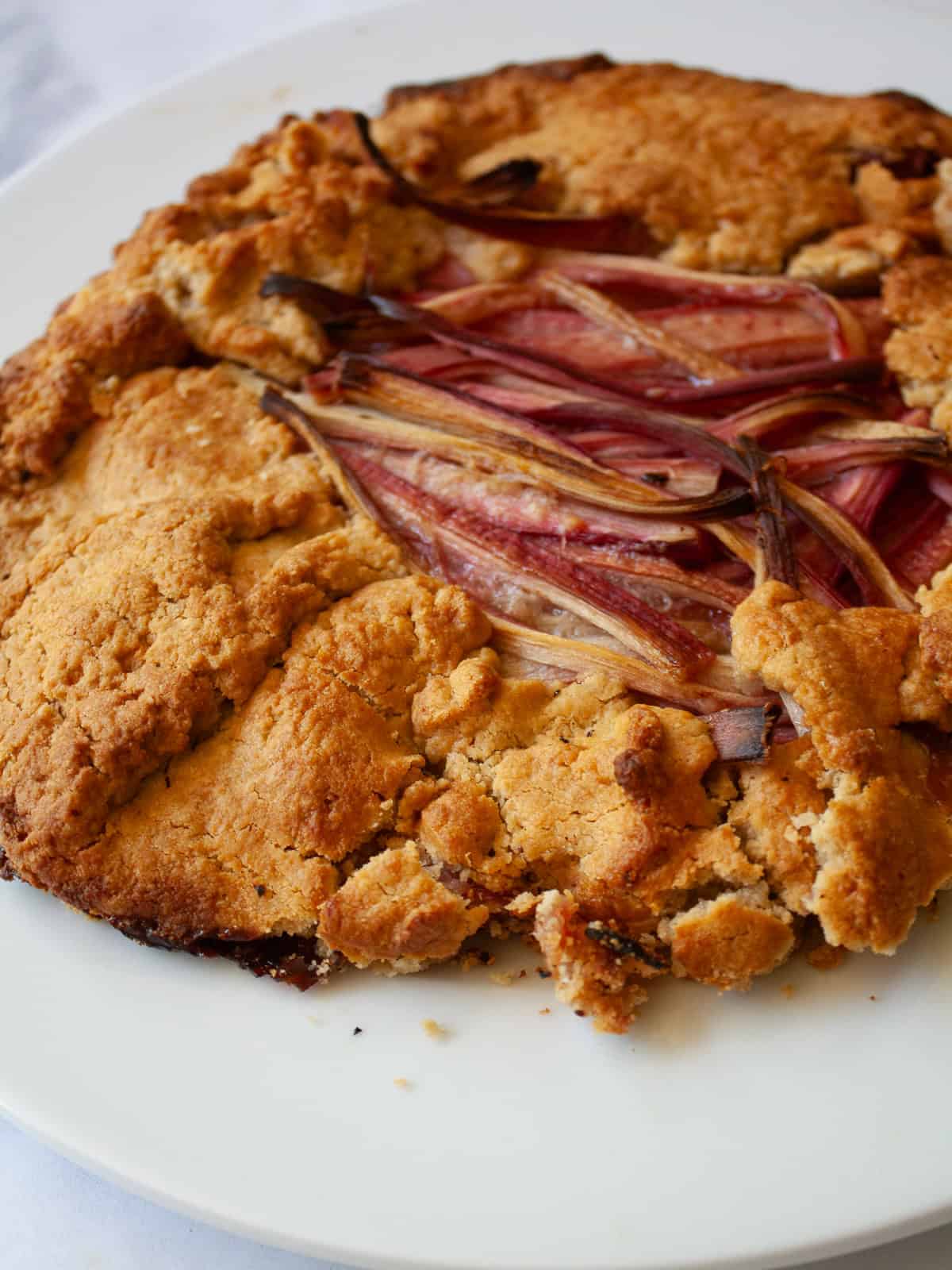 A tender and flaky gluten-free pastry wraps around sweet-tart slices of rhubarb in this rustic gluten free rhubarb galette. A baked gluten free rhubarb galette.