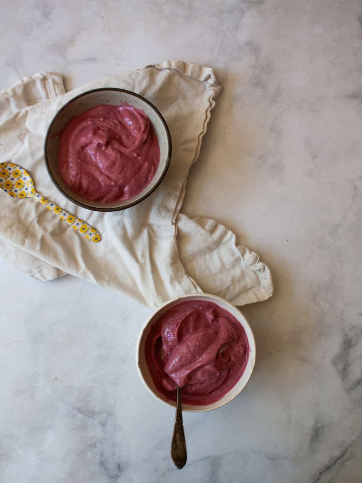 Just two ingredients - fruit and yogurt - plus a food processor are needed to make this refreshing and easy homemade Greek frozen yogurt. Two bowls of homemade Greek frozen yogurt on a napkin.